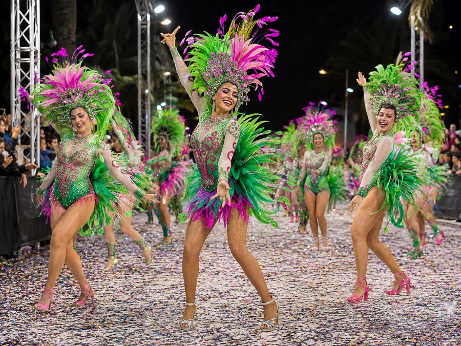 Comparsa de Carnaval con trajes de plumas verdes y rosas desfilando