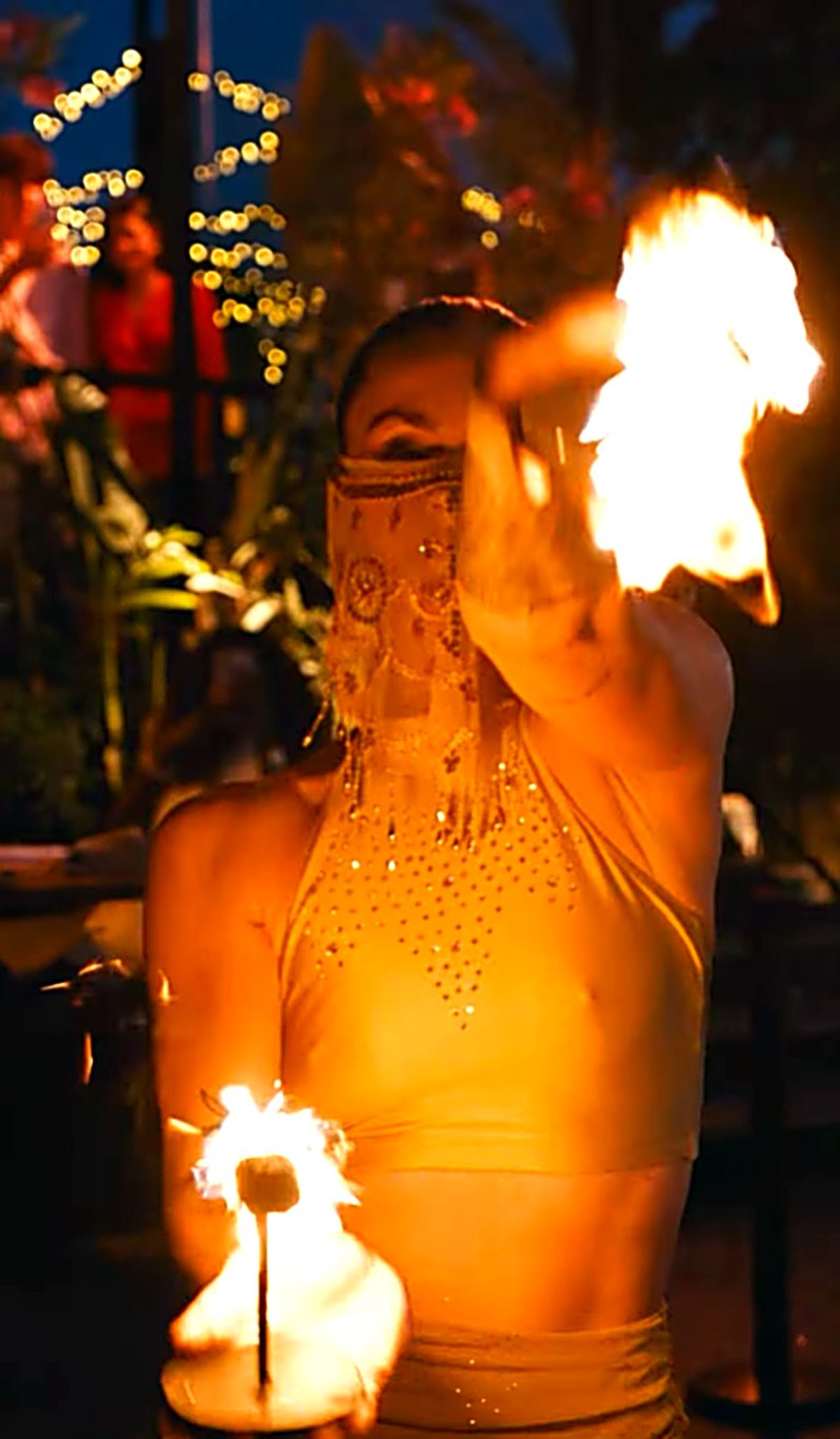 Bailarina con vestuario dorado y velo realizando un número de fuego